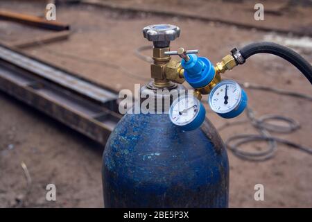 Primo piano della bombola di ossigeno blu con sensori di pressione sul cambio. Attrezzature per il taglio a gas di metalli. Lavorazione del metallo in un cantiere. Foto Stock