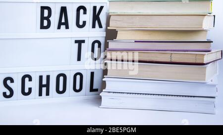 Scatola luminosa con testo DI RITORNO A SCUOLA e libri su sfondo bianco Foto Stock