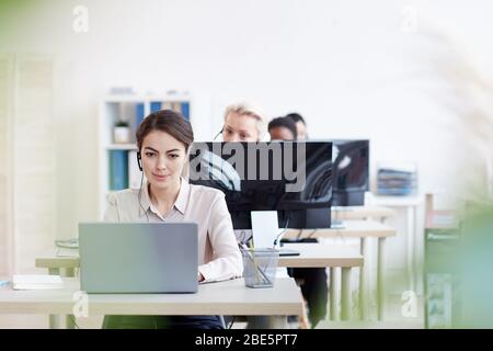 Ritratto delle operatrici dell'helpdesk di sesso femminile che si siedono a riga , attenzione su giovane donna elegante che parla con il cliente tramite cuffia, spazio di copia Foto Stock