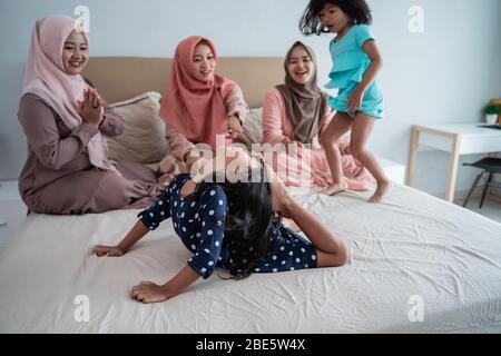 Tre madre asiatica godere giocare con la figlia in camera da letto quando l'attenzione del governo per ancora rimanere a casa Foto Stock