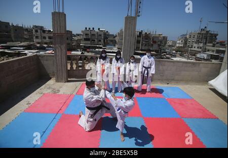 Palestina, striscia di Gaza città di Rafah. 12 aprile 2020. Istruttore di Karate Palestinese Khaled Sheikh al-Eid (L), si allena con uno dei suoi figli, sul tetto della casa, nella città meridionale della striscia di Gaza, Rafah, il 12 aprile 2020. Credit: Khaled Omar/Xinhua/Alamy Live News Foto Stock