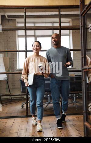 Immagine di giovani colleghi multietnici femminili e maschili che parlano insieme mentre lavorano in ufficio Foto Stock