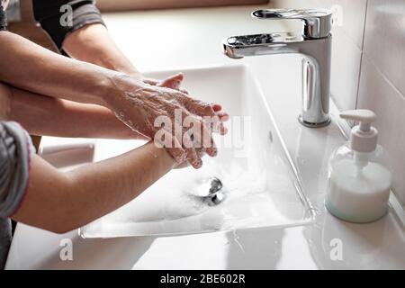 Madre che insegnava a sua figlia come lavare correttamente le loro mani con sapone per prevenire l'infezione da coronavirus Foto Stock