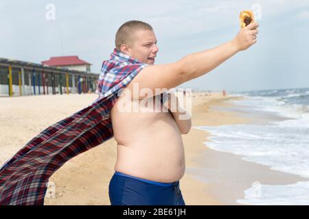 Il divertente uomo obeso in costume da eroe tiene il blaster giocattolo al  tempio su sfondo viola Foto stock - Alamy