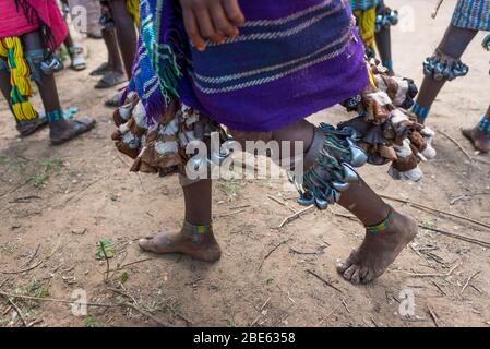 Ballerini con campane sulle gambe a Mursi tribù etnico gruppo venuta di età bull jumping cerimonia, Jenka, Etiopia, Foto Stock