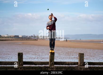 Portobello, Edimburgo. Scozia, Regno Unito. 12 aprile 2020. Domenica di Pasqua pomeriggio in tempo soleggiato il pubblico è all'aperto, allenandosi e camminando sulla spiaggia di Portobello. La spiaggia e il lungomare erano molto tranquilli e la gente si stava esercitando per lo più a distanza sociale. Nella foto; giocoleria uomo sulla spiaggia di portobello. Iain Masterton/Alamy Live News Foto Stock