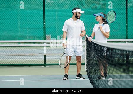 Coppia multietnica che discute gioco dopo aver giocato a tennis all'aperto Foto Stock