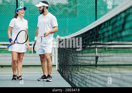 Giovane donna che ride a scherzo di compagno di squadra dopo aver giocato a tennis insieme Foto Stock