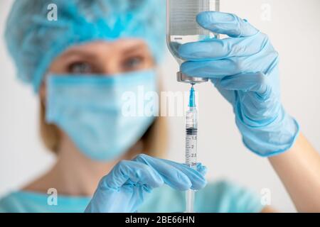 Flacone e siringa per iniezione in mano dell'infermiere. Flaconcino di vetro per uso medico per la vaccinazione. Attrezzatura scientifica, farmaco liquido o vaccino. Concetto di medicina Foto Stock