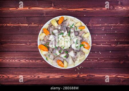 Piatto di Beshbarmak. Tagliatelle con agnello e cipolla primo piano su un piatto sul tavolo. Vista dall'alto orizzontale Foto Stock