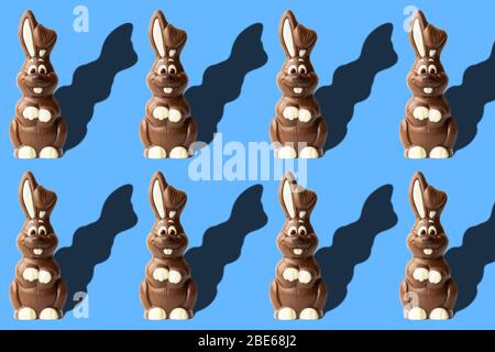 Modello pasquale con conigli di cioccolato su sfondo blu. Foto di Pasqua con coniglio al cioccolato al latte Foto Stock