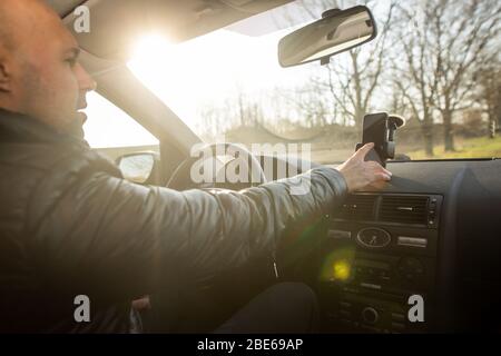 Uomo che imposta il GPS sul mobile prima della sua guida, assisstant durante la guida dell'automobile, concetto di trasporto Foto Stock