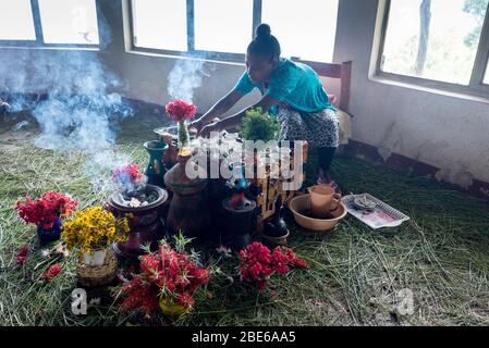 Una giovane donna prepara il caffè per gli ospiti del ristorante, mentre l'incenso brucia tra i fiori, Addis Abeba, Etiopia. Foto Stock