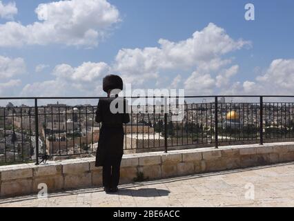 Gerusalemme, Israele. 12 aprile 2020. Un Ebreo ultra-ortodosso prega sul Monte degli Ulivi, che domina la Città Vecchia di Gerusalemme, domenica 12 aprile 2020. Il governo israeliano ha dispiegato una polizia del 1,000 per imporre una chiusura completa dei quartieri religiosi ebrei con il più alto tasso di coronavirus a Gerusalemme. Secondo il Ministero della Salute circa il 75% degli infetti a Gerusalemme vive nei quartieri ultra-ortodossi. Foto di Debbie Hill/UPI Credit: UPI/Alamy Live News Foto Stock