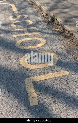Scuola gialla mantenere zona chiara dipinta su asfalto fuori ingresso scuola in una soleggiata mattina di primavera. Parcheggio, rientro e servizio di prelievo non consentiti. Foto Stock