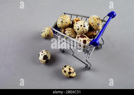 Uova di quaglia in un carrello da un supermercato su uno sfondo di cemento Foto Stock