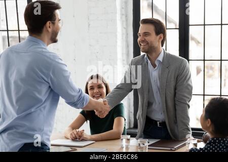 Felice uomo colleghi stretta di mano chiudere l'affare in ufficio Foto Stock