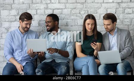 Persone diversificate e mirate si siedono in fila utilizzando i notebook Foto Stock