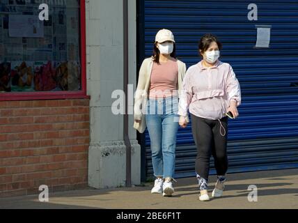 Due donne fuori camminare, indossando maschere facciali, durante il blocco del virus Corona Foto Stock