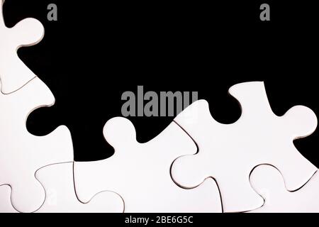 Pezzi di puzzle bianco incompiuto su sfondo nero Foto Stock