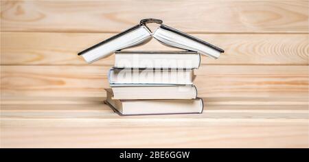 Quarantena dello sfondo. Concetto di soggiorno a casa. Casa fatta con libri impilati su sfondo di legno Leggi libri sfondo. COVID-19 impatto. Regola di base di Foto Stock