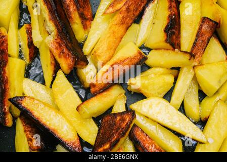 Patate fritte in una padella. Zeppe di patate cotte con sale e spezie primo piano. Fast food. Vista dall'alto Foto Stock