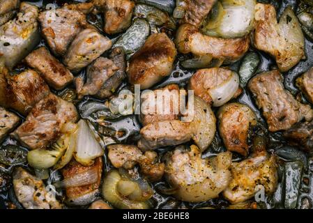 Cottura della carne in una padella. Carne, cipolle e spezie sono alla griglia. Pezzi di carne primo piano. Vista dall'alto, disposizione piatta Foto Stock