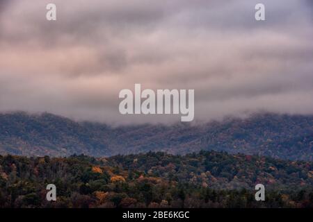 Nuvole a basso appeso sopra la foresta d'autunno nelle fumose Foto Stock