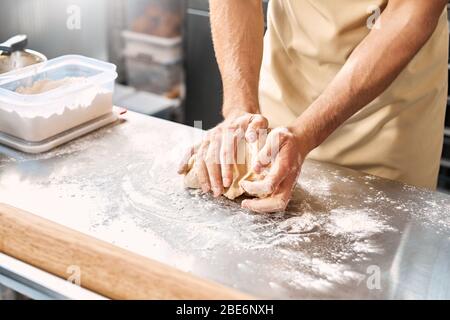 Giovane adulto che lavora con l'impasto in cucina Foto Stock