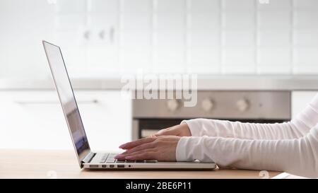 Primo piano delle mani della donna utilizzando e digitando la tastiera del laptop sul tavolo di legno dell'ufficio domestico. Foto Stock