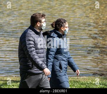 Berks County, Pennsylvania, USA, 11 aprile 2020- giovane coppia passeggiate nel parco indossando maschere. Il CDC raccomanda a tutti di indossare maschere facciali protettive Foto Stock