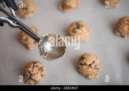 Una foto di una teglia con pasta e scoop di biscotti crudi al cioccolato Foto Stock