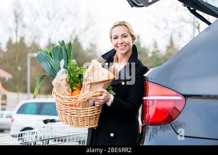 Donna che carica i generi alimentari dopo lo shopping nel tronco della sua auto Foto Stock