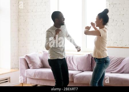 Giovane coppia afroamericana sorridente che balla in soggiorno. Foto Stock
