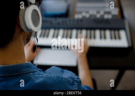 Primo piano sfocato. Maschile music arrangiatore mani componendo canzone su midi piano e apparecchiature audio in studio di registrazione digitale. L'uomo produce elettronica Foto Stock