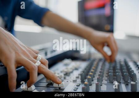 Mano su un mixer, che aziona il leader. Ingegnere del suono che lavora al pannello di mixaggio nello studio di registrazione. Mixer audio con regolazione manuale. Primo piano. Foto Stock