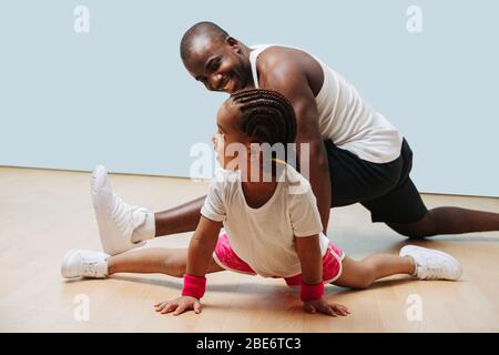 Padre e figlia si esercitano in quarantena insieme, allungando le gambe Foto Stock