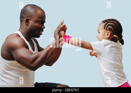 Padre che addestrò la sua figlia piccola a scatola, facendo faccia seria. Blu Foto Stock