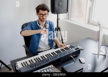 pollici giù. Compositore ha a disposizione i tasti del pianoforte nello studio di registrazione. Tecnologia di produzione musicale, l'uomo sta lavorando a pianino e alla tastiera del computer. Cattivo Foto Stock