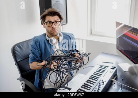 Non sa cosa fare con fili, cavi e cavi. DJ in studio di trasmissione. Produttore di musica sta componendo una canzone su tastiera sintetizzatore e. Foto Stock