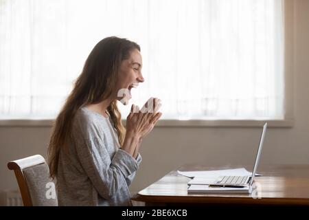 Entusiasta donna millenaria che legge le e-mail con buone notizie. Foto Stock