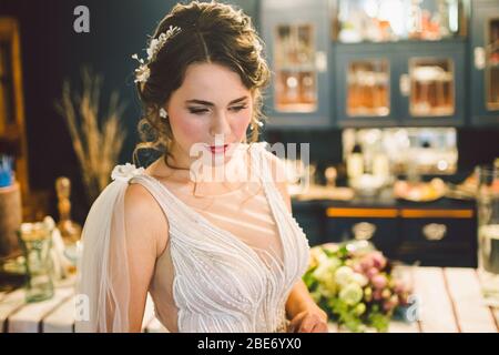 Bellissima sposa con trucco di nozze e corona di gioielli. Moda nuziale posa in casa. Mattina di bella sposa. Giorno del matrimonio. Donna finale appena fatta Foto Stock