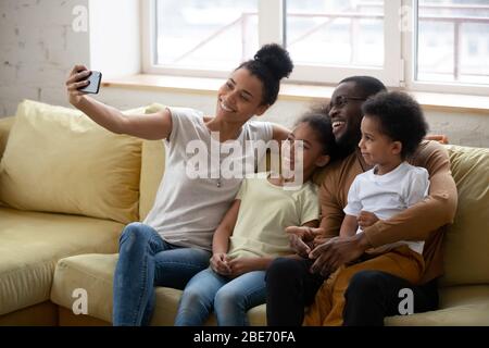 Genitore Africano Americano con due bambini che prendono selfie.