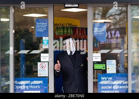 Guardia di sicurezza che controlla gli acquirenti che entrano ed escono dal supermercato Tesco Express, la domenica di Pasqua. Foto Stock