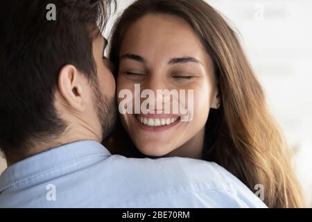 Affettuoso uomo coccolante moglie, sussurrando parole dolci in orecchio. Foto Stock