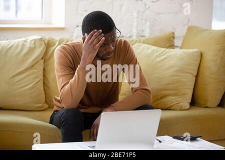 Rovesciate l'uomo che tocca la testa utilizzando la calcolatrice e il laptop per il calcolo. Foto Stock
