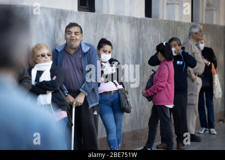 Buenos Aires, Argentina - 04 aprile 2020: Persone non identificate che attendono al di fuori delle banche facendo lunghe code durante la quarantena a Buenos Aires, AR Foto Stock