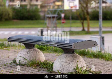 Panchina deserta in un parco cittadino in primo piano concettuale di luoghi urbani vuoti a causa del blocco per il coronavirus o Covid-19 pandemic Foto Stock