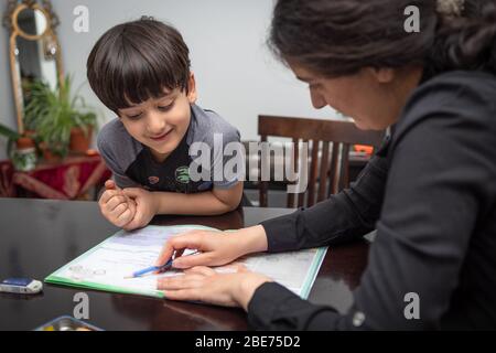 Mamma che insegna e aiuta suo figlio a fare lavoro a casa, scuola a casa in mezzo allo scoppio del covid-19 Foto Stock