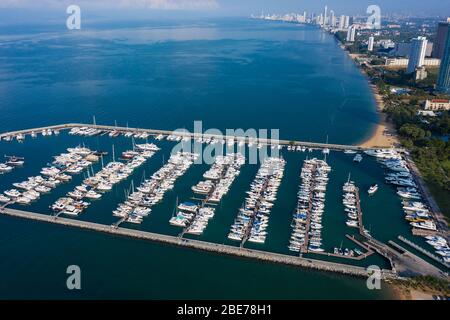 Vista aerea di un yacht a motore bianco. Lo yacht entra nella baia nel parcheggio. Molti yacht diversi, catamarani ormeggiati ai moli. Yacht e tr costosi Foto Stock